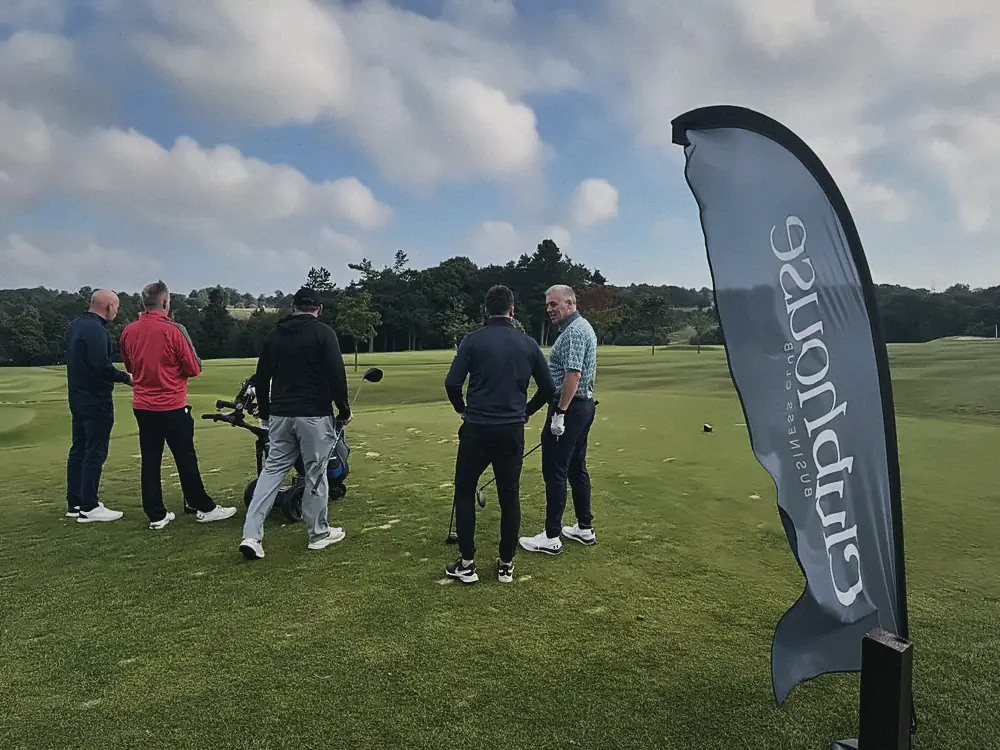 Players gathering by a Clubhouse flag at the Gartcairn FC charity golf day