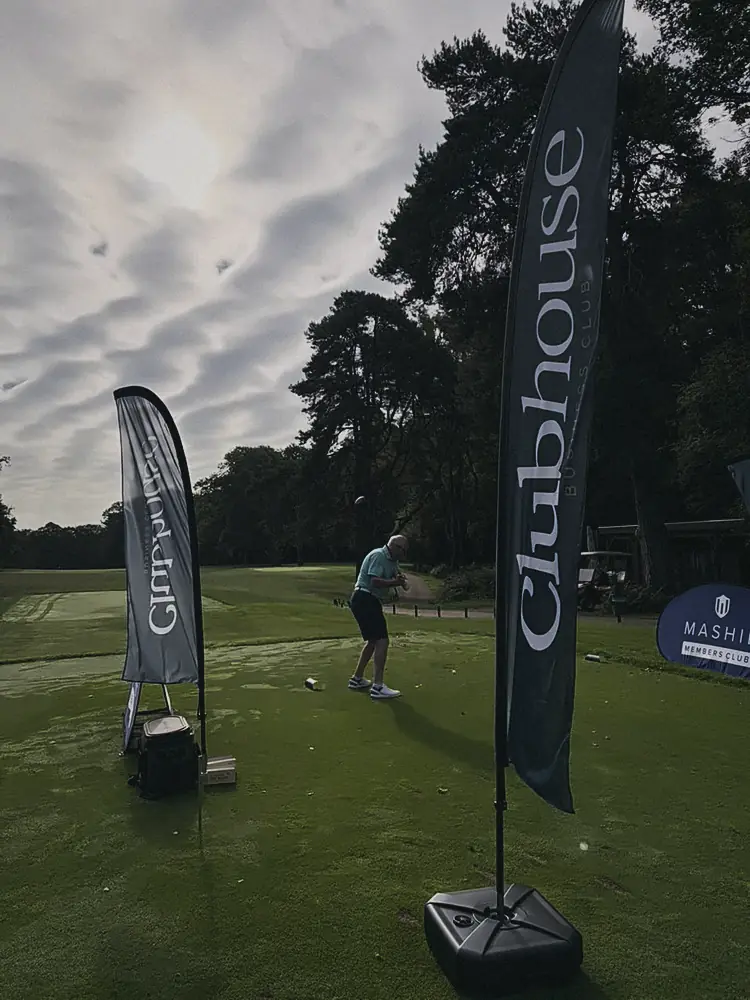 A player on the tee between Clubhouse flags at Woburn