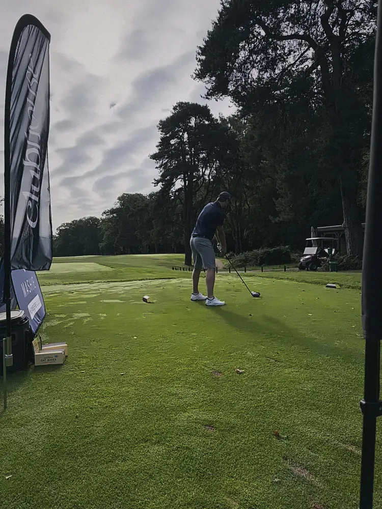 A member lining up his drive on a tee framed by tall pines at Woburn