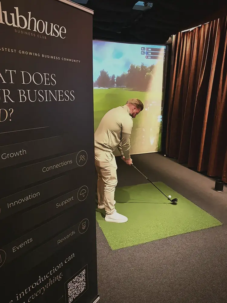 A member mid-swing beside the Clubhouse banner