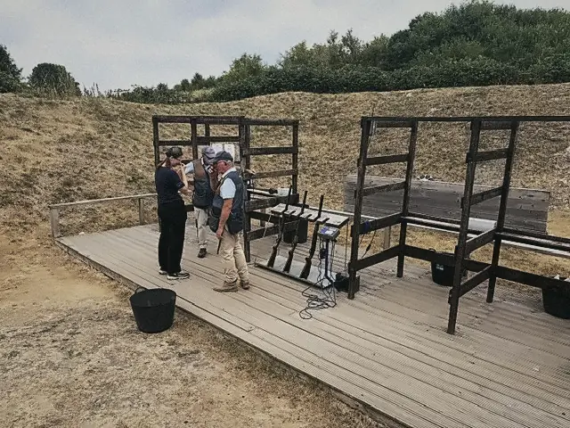 An instructor coaching members at a shooting stand